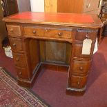 A Victorian mahogany and walnut kneehole desk, with rounded edge, having eleven drawers, raised on
