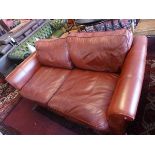 A contemporary burgundy leather three seater sofa, raised on block feet