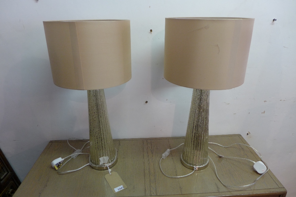 A pair of contemporary glass table lamps, of fluted tapered form, with cream shades, H.67cm