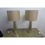 A pair of contemporary glass table lamps, of fluted tapered form, with cream shades, H.67cm