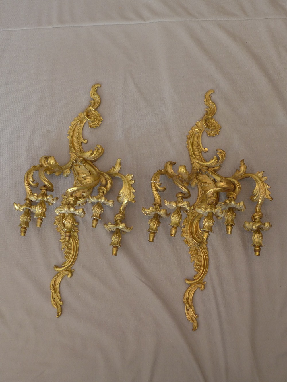 A pair of early 20th century Rococo style ormolu three branch wall lights