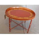 A Chinese red and gilt painted table, with oval toleware tray to top decorated with gilt flowers,