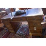 An early to mid 20th century yew wood pedestal desk, with red leather skiver, nine drawers, raised