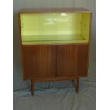 A mid 20th century teak cocktail cabinet, with two glass sling doors, above two cupboard doors,