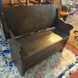 An early 20th century carved oak bench with folding back
