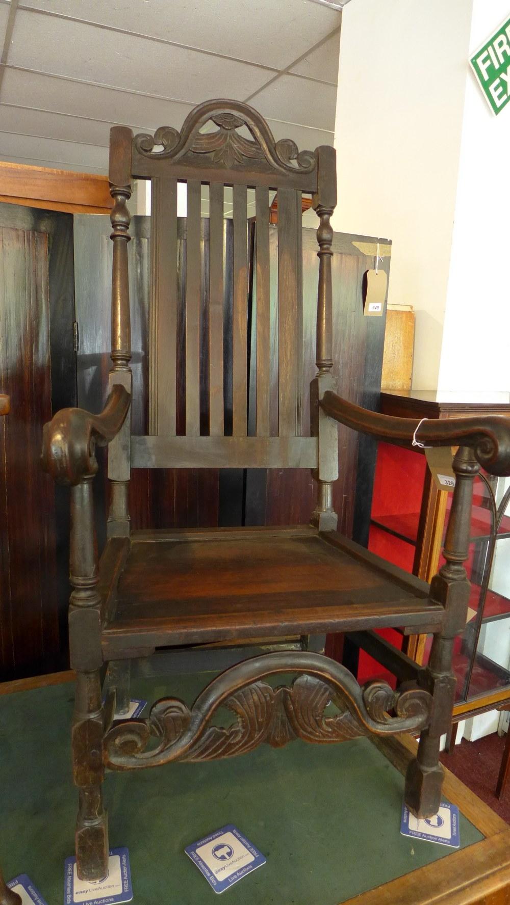 An 18th century oak throne chair, with scroll arms and carved stretcher