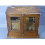 An early 20th century oak smokers cabinet, hinged lid, bevelled glass, four drawers, stepped base,