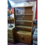 A mid 20th century light oak bookcase with two sliding glass doors over two cupboard doors raised on
