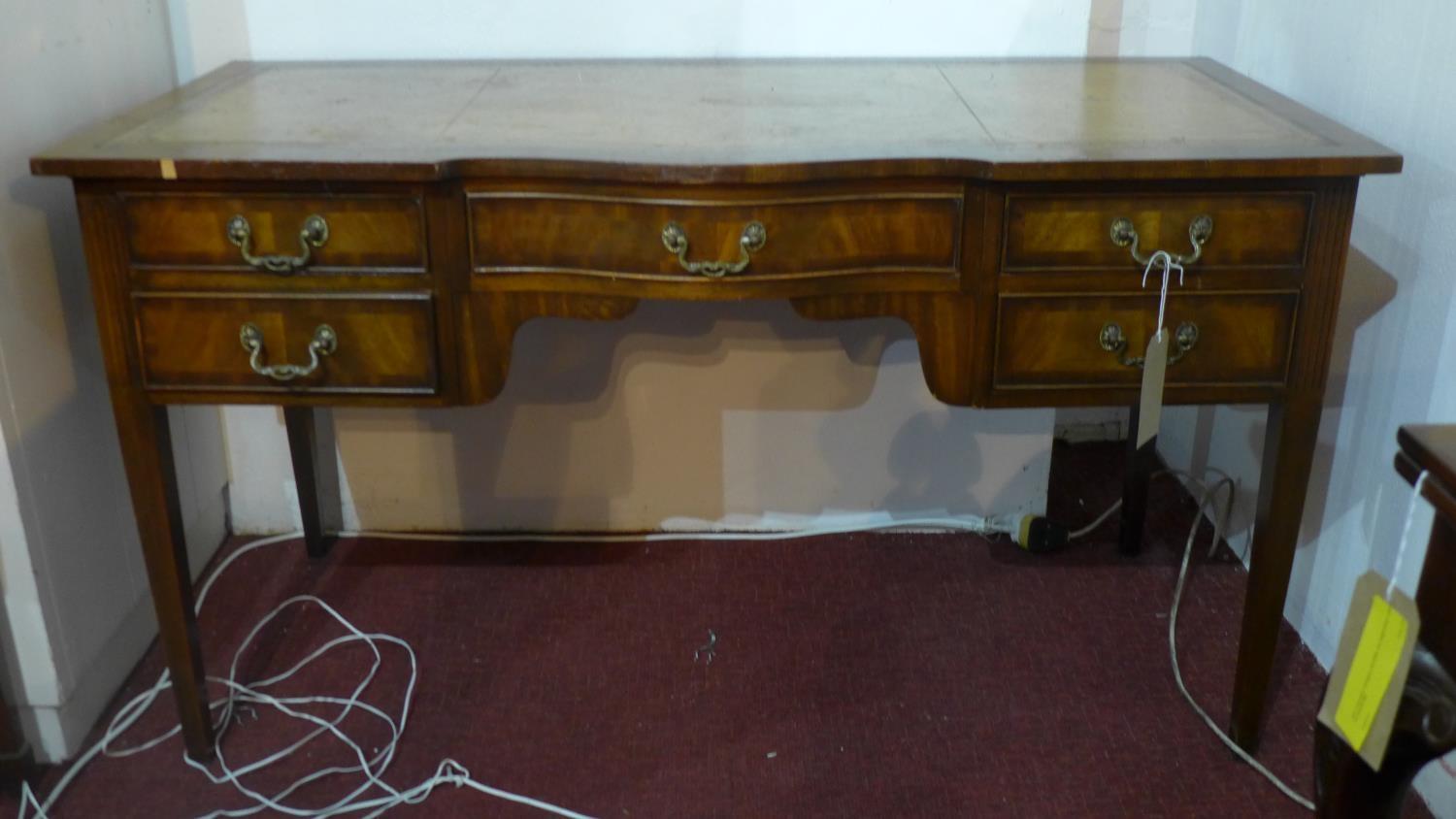 A mid 20th century ladies mahogany bow breakfront writing table, leather skiver, five drawers, two