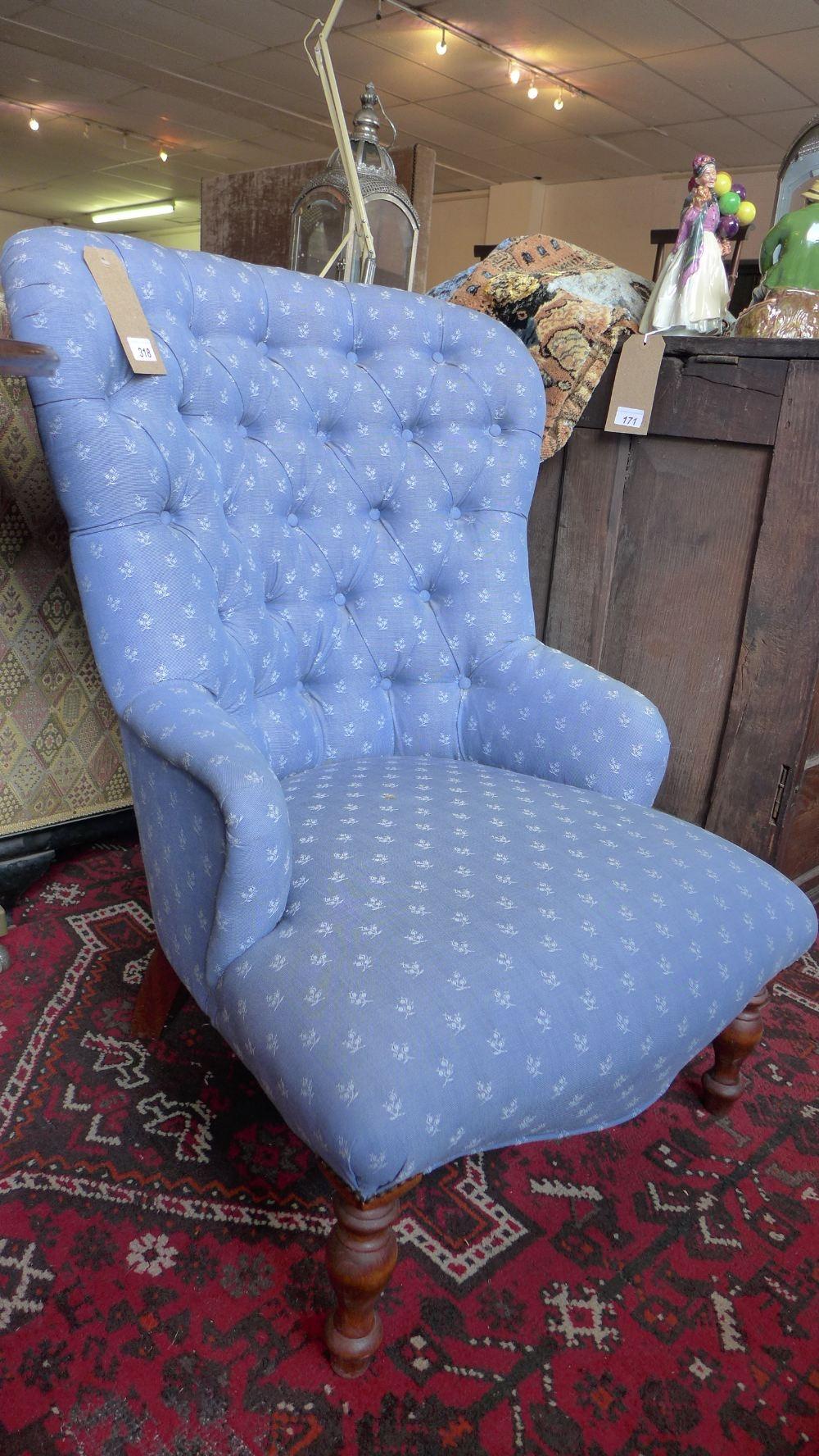 A Victorian style spoon back armchair, with blue floral button back upholstery, raised on turned