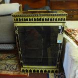 A Regency ebonised pier cabinet, painted with stylised flowers, having glazed door revealing two