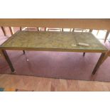 A brass coffee table, having intricately carved giltwood panel with pierced decoration depicting