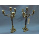 A pair of bronze three branch four light Corinthian column candelabra, with ebonised column raised