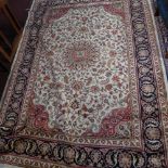 A Kashan style carpet, with central floral medallion on a beige ground, contained by floral