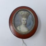 An 18th century miniature portrait of a lady, mounted in white metal on the lid of an amber