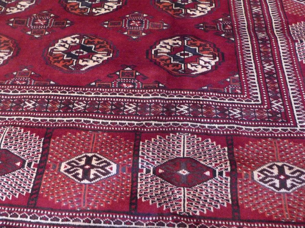 A North East Persian Turkoman carpet, repeating Tekkeh motifs on a madder ground within stylised - Image 3 of 3