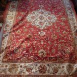 A Kashan style carpet, with central floral medallion on a red ground, contained by floral borders,