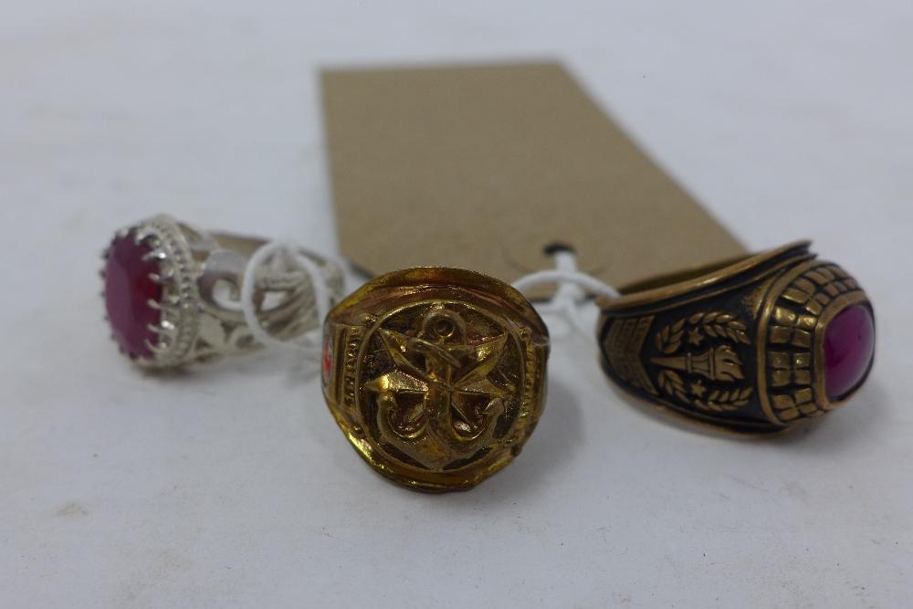 A brass and garnet graduation ring, together with a gilt metal ring inset with two rubies and anchor