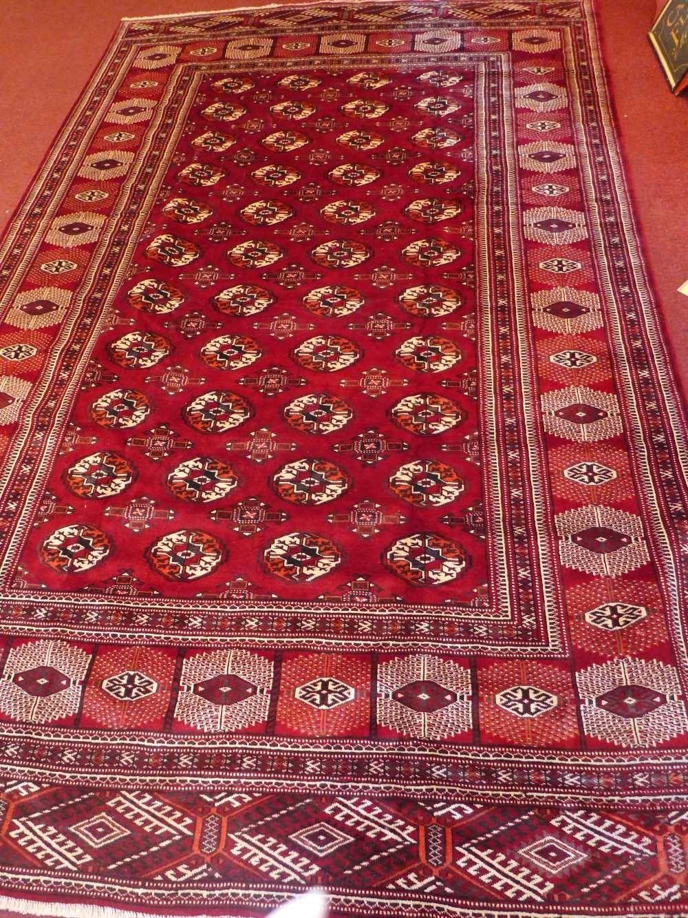 A North East Persian Turkoman carpet, repeating Tekkeh motifs on a madder ground within stylised