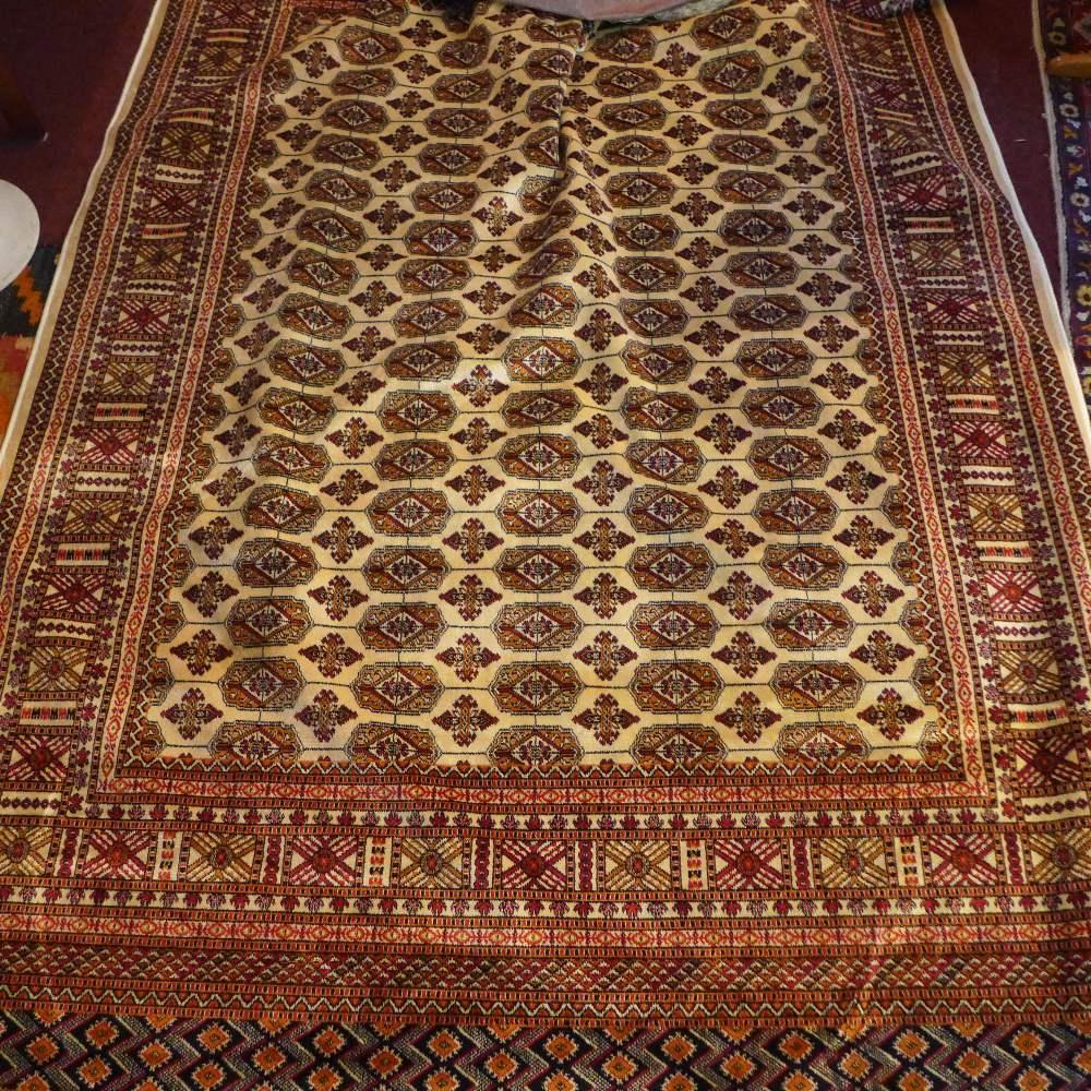 A Bokhara style carpet, with elephant pad motifs on a beige ground, contained by geometric border,