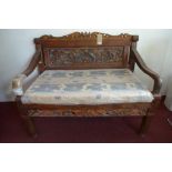 A Balinese carved hardwood bench, H.101 W.127 D.70cm, one arm needs repairing