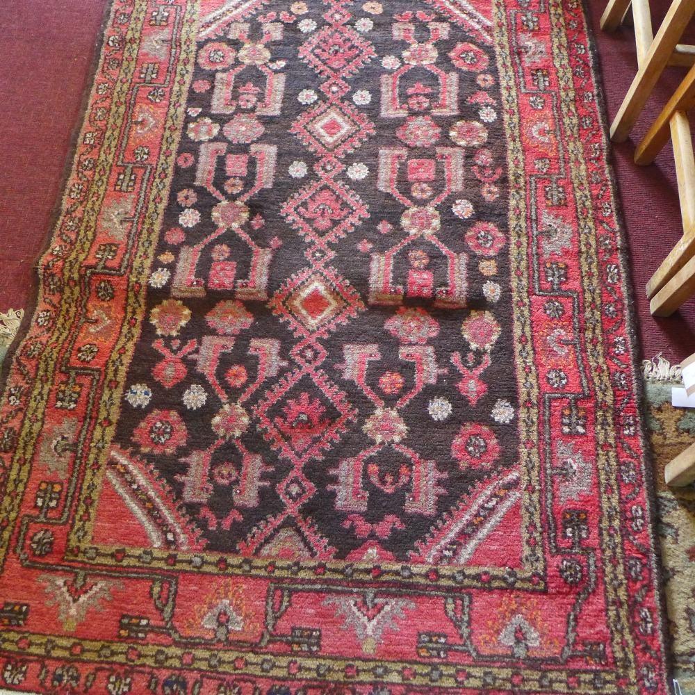 A Persian rug, with medallions on a brown ground, contained by floral borders on a red ground, 180 x