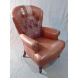 A Victorian style spoon back armchair, with tan leather button back upholstery, raised on turned