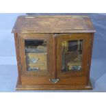 An early 20th century oak smokers cabinet, hinge lid, bevelled glass, four drawers, stepped base,