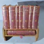 An Asprey and Co. Ltd Reference Library, in a oak book rest holding eight leather bound books,