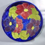A Moorcroft plate, decorated with flowers, stamped Moorcroft and signed WM to base, Diameter 30.5cm