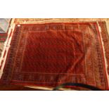 A Bokhara style carpet, with elephant pad motifs, on a red ground, contained by geometric borders,