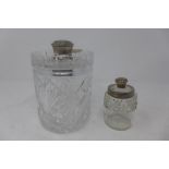 A cut glass silver topped decanter together with one other silver collared cut glass table jar