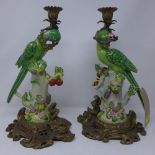 A pair of Meissen style porcelain and gilt metal candlesticks, with porcelain parrot perched on a
