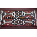 An Afghan woollen carpet, with geometric design, on a red and black ground, 273 x 128cm