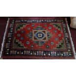 A Persian rug with central geometric medallion on a red ground, contained by geometric motifs and