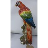 A Sitzendorf porcelain parrot, seated on a tree trunk, marked to base, H.35cm, with break to tail