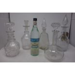 Five glass decanters together with a bottle of ouzo