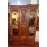An Art Nouveau wardrobe, with central carved panel flanked by two mirrored cupboard doors with