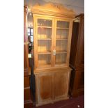 A mid 20th century pine bookcase, with two glazed doors over two cupboard doors, raised on stepped