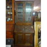 An early 20th century oak bureau bookcase with two lead glass doors, above drop flap and two