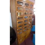 An early to mid 20th century light oak Haberdashery cabinet with 24 glass fronted drawers, above two