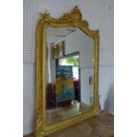 An early 20th century Rococo style gilt wood over mantle mirror, carved floral crest, beaded