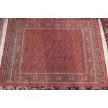 A Bokhara style rug, the central repeated motifs on a red ground within multiple borders L.190cm W.