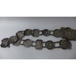 A Chinese white metal belt, the plaques decorated with flowers, dragons and Chinese characters,