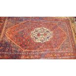 An antique Persian Caucasian rug, the central ivory medallion on a ruby ground within a stylised