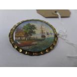 A 19th century gilt metal brooch, hand painted with ships leaving a bay