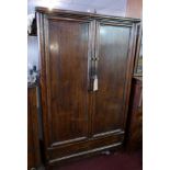 A 20th century Chinese elm wedding cabinet, with two doors enclosing shelves and two drawers