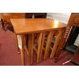 A 1970s teak nest of tables, comprising a large table and four slide out tables, H.56cm W.62cm D.