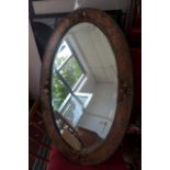 An Art Nouveau copper wall mirror, the bevelled oval plate within a repousee pressed frame, H.78cm