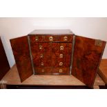 A Victorian burr walnut table top cabinet, with two doors enclosing 11 drawers having brass ring